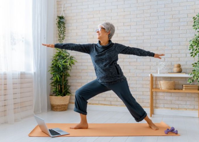 Seniorka na macie ćwiczy jogę dla seniora online